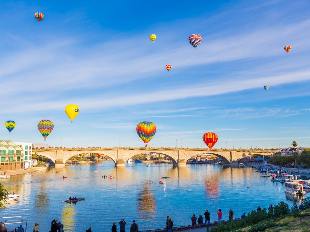 A view of the London Bridge at Lake Havasu City with hot air balloons in the sky on a clear day.