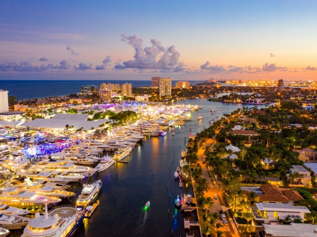 An aerial view of Fort Lauderdale's Intracoastal Waterway at dusk, with marinas full of yachts and city lights glowing along the waterfront.