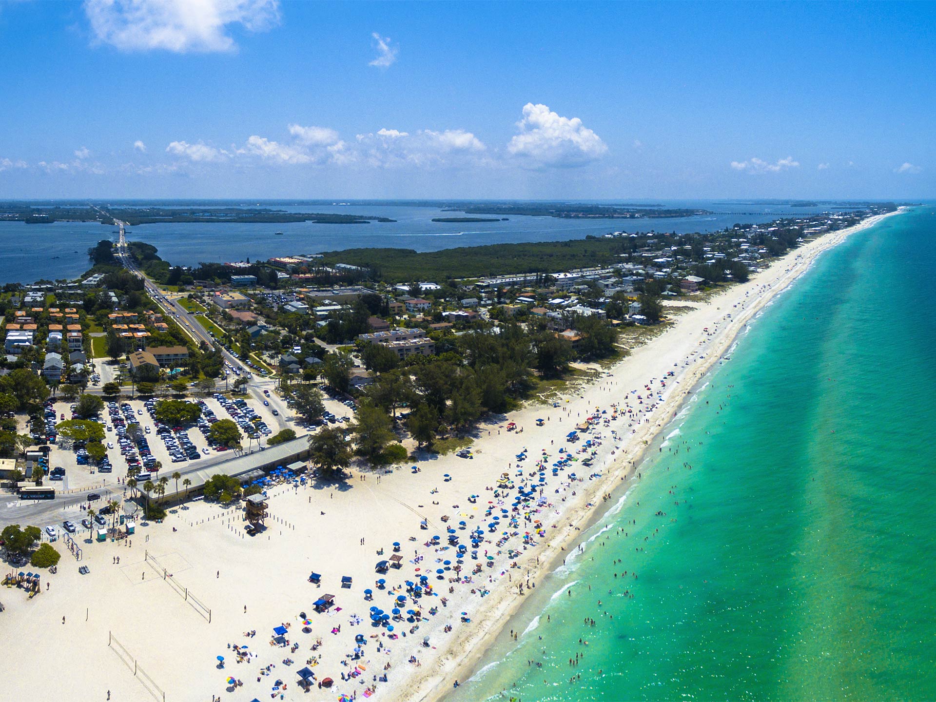 An aerial view of Anna Maria Island with beaches facing the Gulf of America on the right and the inshore bays on the left