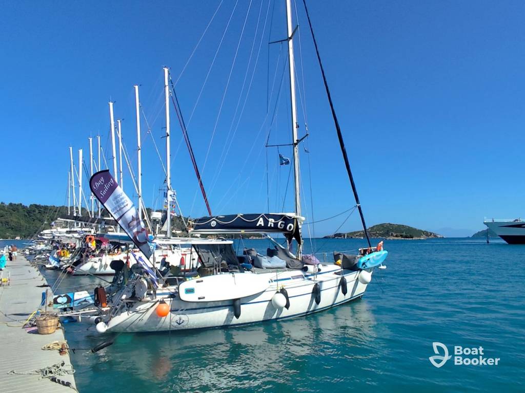 Several sailboats are docked along a marina pier on a clear, sunny day with calm blue water. There's a distant island visible, but you won't spot any TUNA or SALMON in sight.