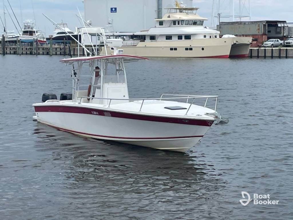 A white and red center console motorboat's floating on a marina with other boats and docks in the background.