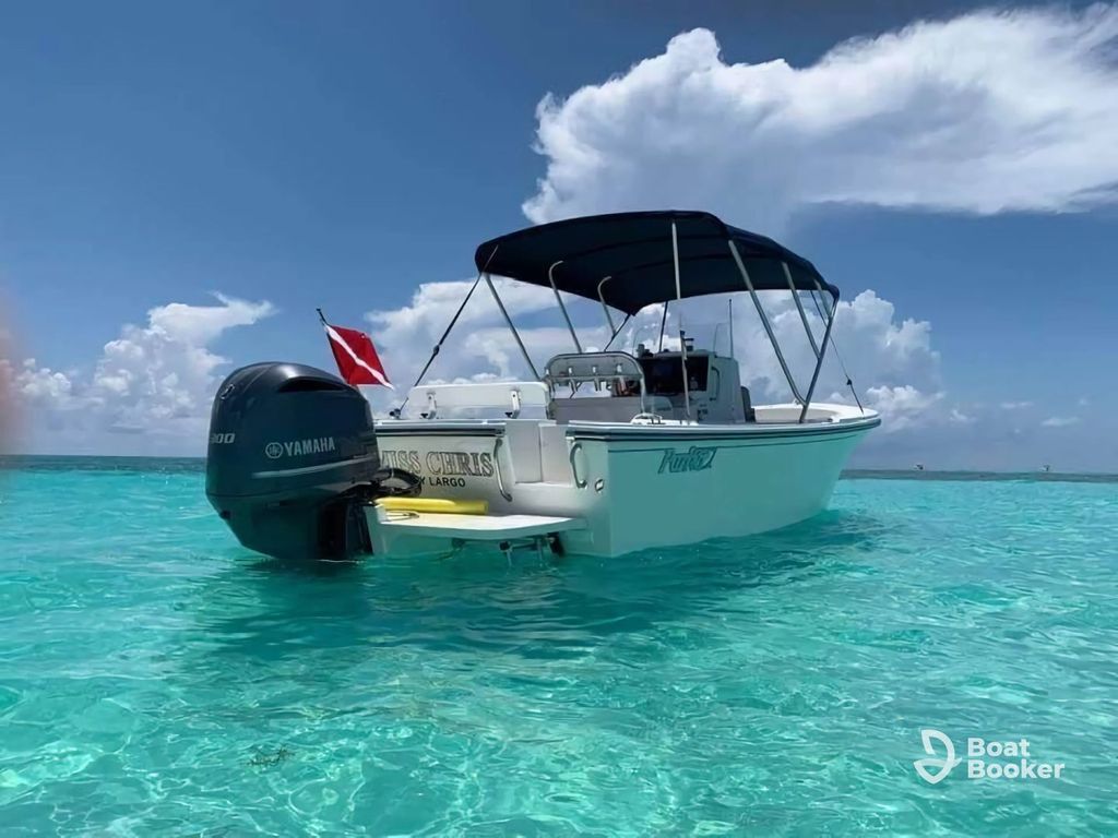 A white motorboat with a Yamaha outboard's floating on clear turquoise water under blue skies, showing a red diver down flag—perfect for those with a Florida boating license.