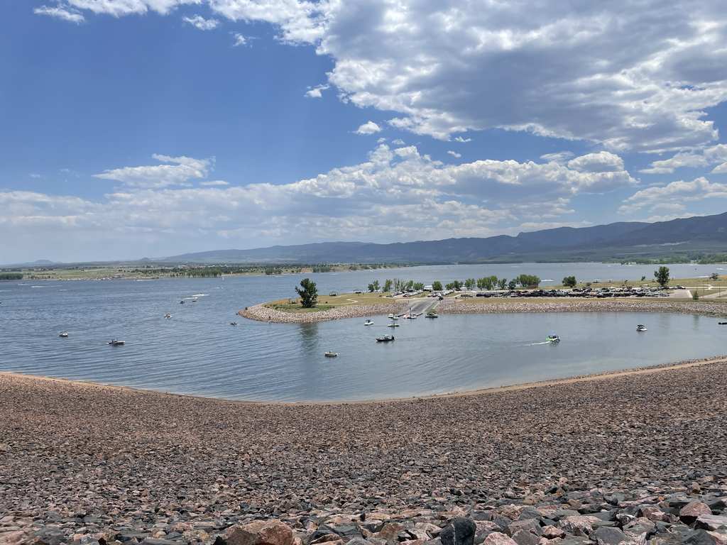 Colorado reservoir surrounded by green hills under a summer sky