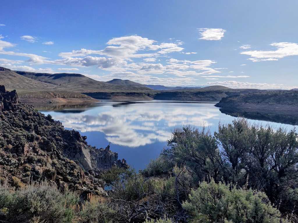 Blue Mesa Reservoir reflecting clouds with sage brush in foreground