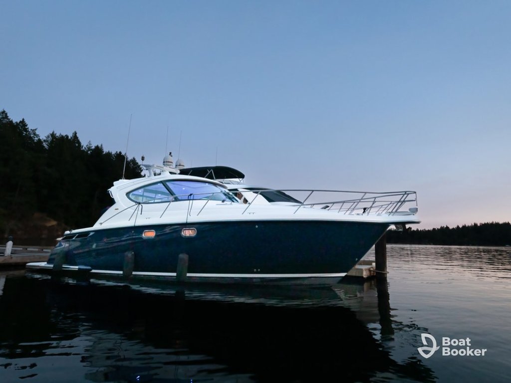A white and navy motor yacht's docked at a pier on calm water at dusk, with forested hills behind—one of the best boating lakes in Washington State.