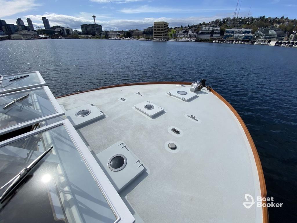 You're looking out from a boat's bow docked on one of Washington State's top boating lakes, with city buildings and hills below a partly cloudy sky.