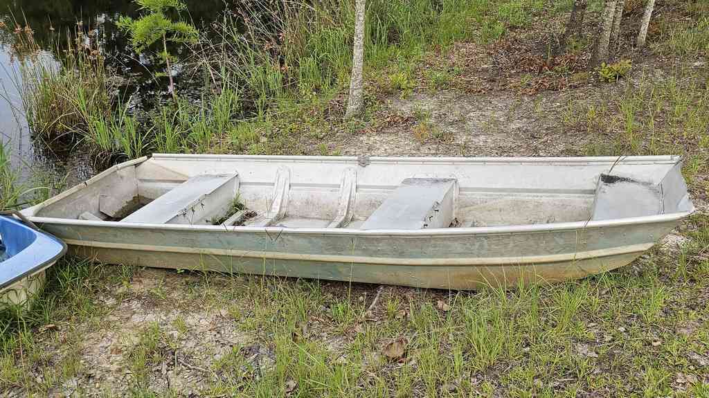 Typical jon boat with flat bottom resting on a calm pond