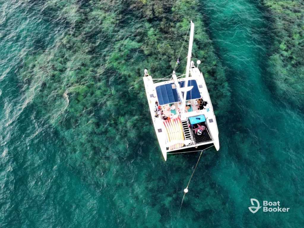 Sailing catamaran under sail on open turquoise water with guests aboard