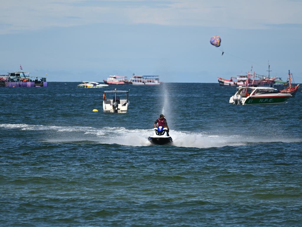 Person zipping across the ocean on a jet ski with boats on the horizon