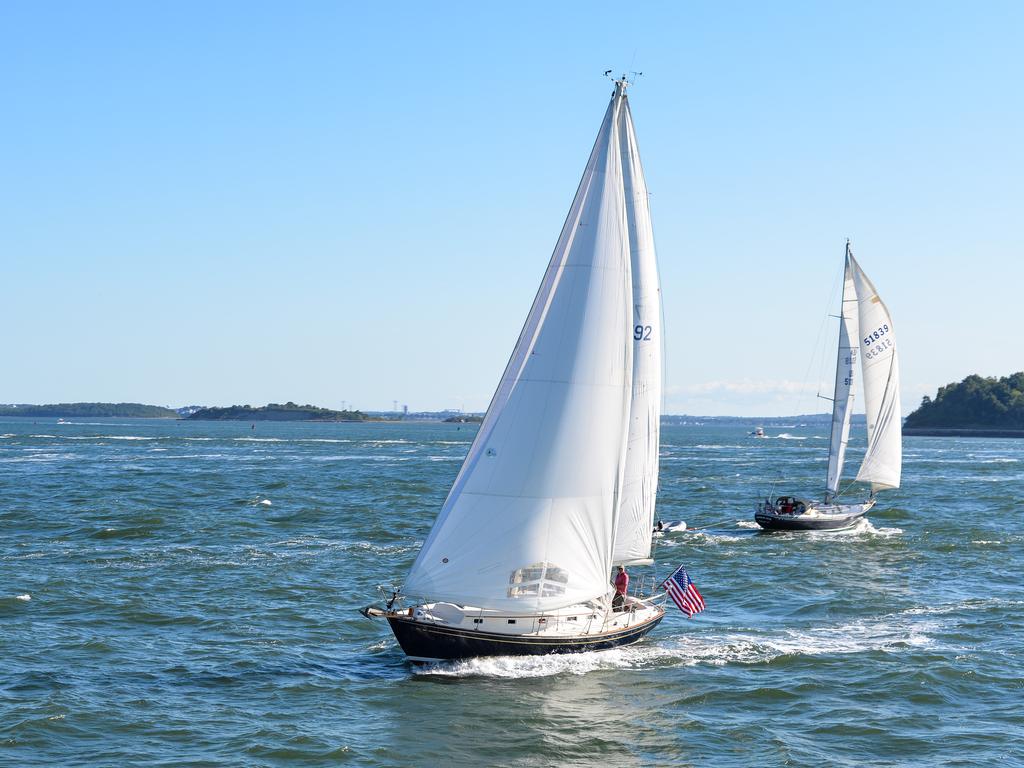 Two sloops sailing across Boston Harbor on a clear day