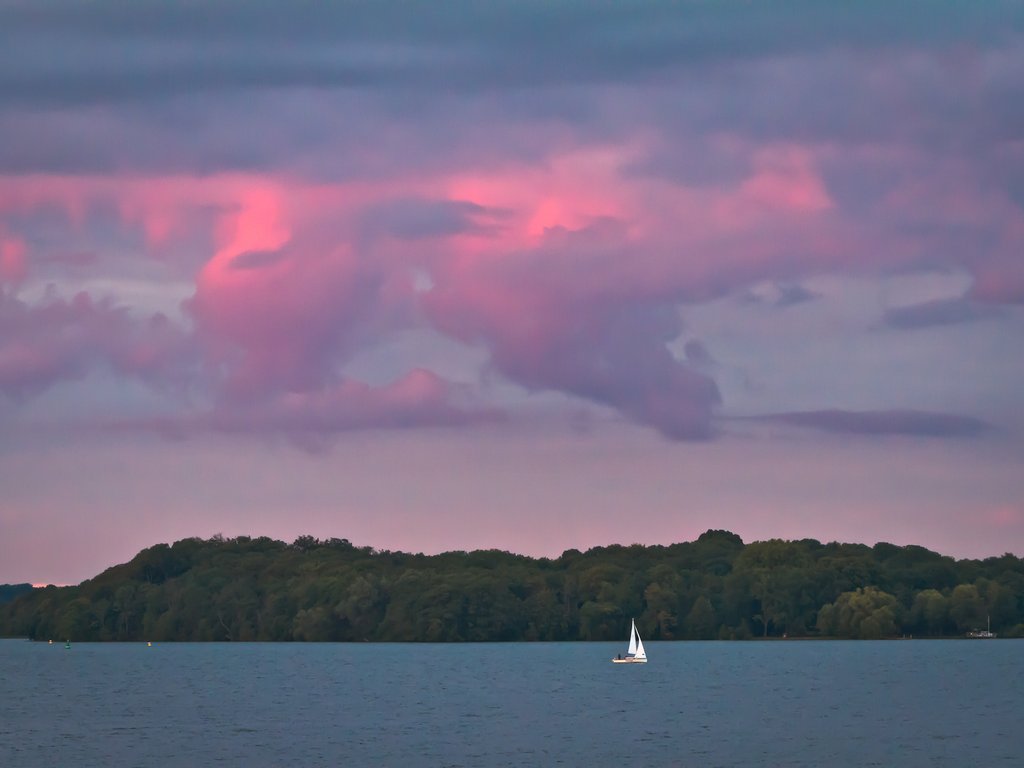 Sailboat gliding across a golden sunset on calm water