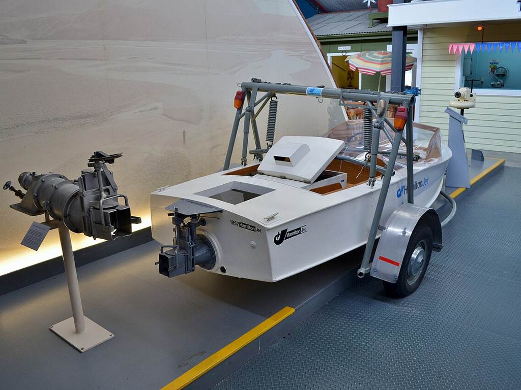 There’s a small white boat with scientific gear on a trailer indoors, right next to another machine display. No fish or species names are shown in the description.