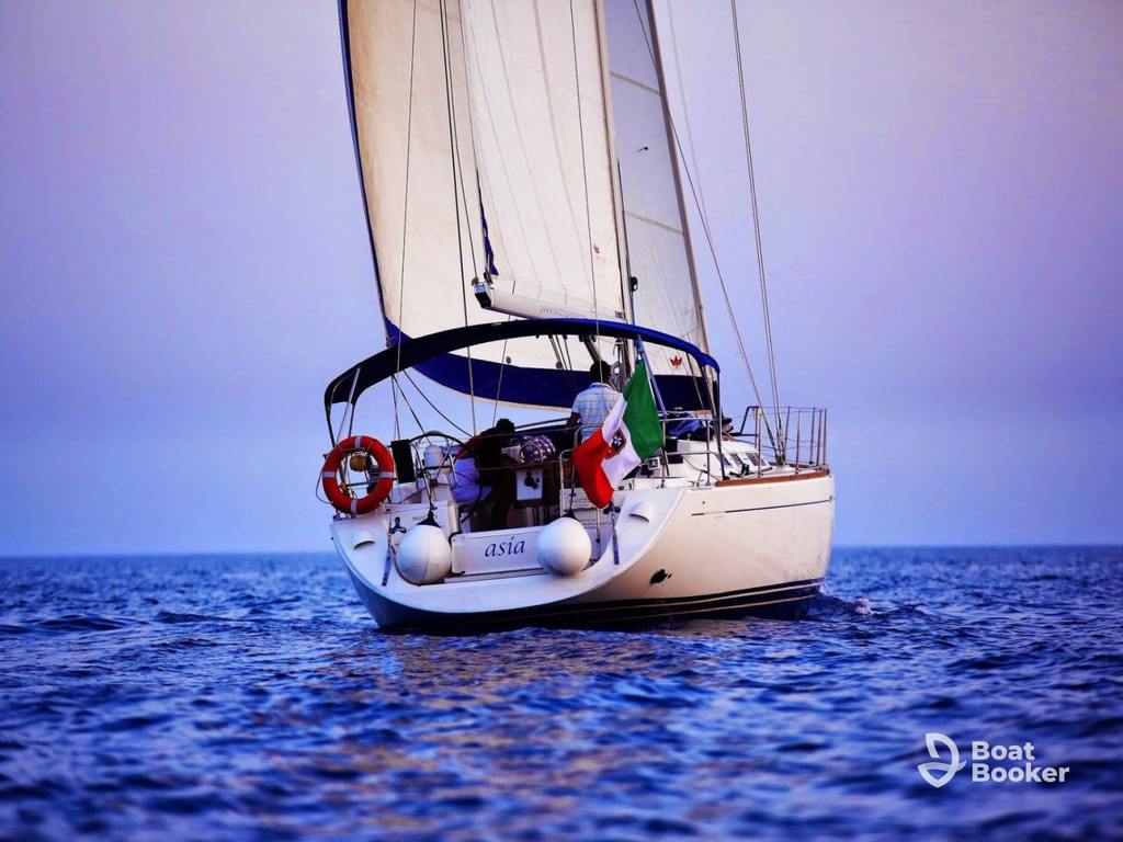 A white sailboat called “Asia” sails on calm blue water with an Italian flag, a life ring, and sailing terms next to the Boat Booker logo in the corner.