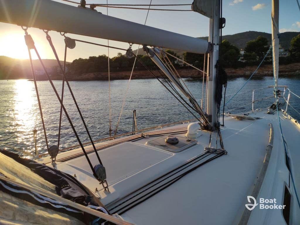 You’re looking out from the sailboat’s deck anchored near the coast at sunset, with calm waters and distant hills creating a peaceful scene—no visible fish or species named in view.