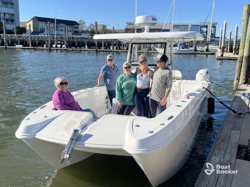 Five people are on a white motorboat docked at a marina, enjoying the day. It’s essential to get a South Carolina boating license for safe and legal boating in this scenic setting.