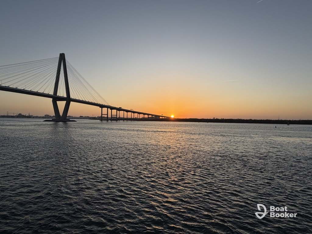 A cable-stayed bridge stretches over a wide river at sunset, with calm water—great for folks exploring with a South Carolina boating license as the sun’s dipping low on the horizon.