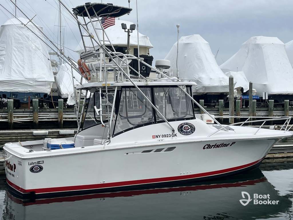 A white fishing boat named “Christine P” is docked at a marina—don’t forget, you’ll need a New York boating license for trips like this. Covered boats are in the background.