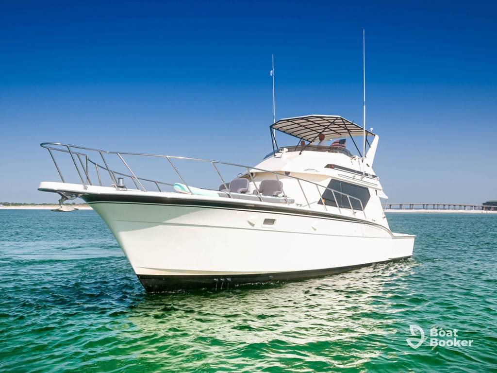 A white motor yacht’s floating on calm greenish-blue water near a bridge, under clear blue skies—ever wondered what a Cuddy Cabin is on boats like this?