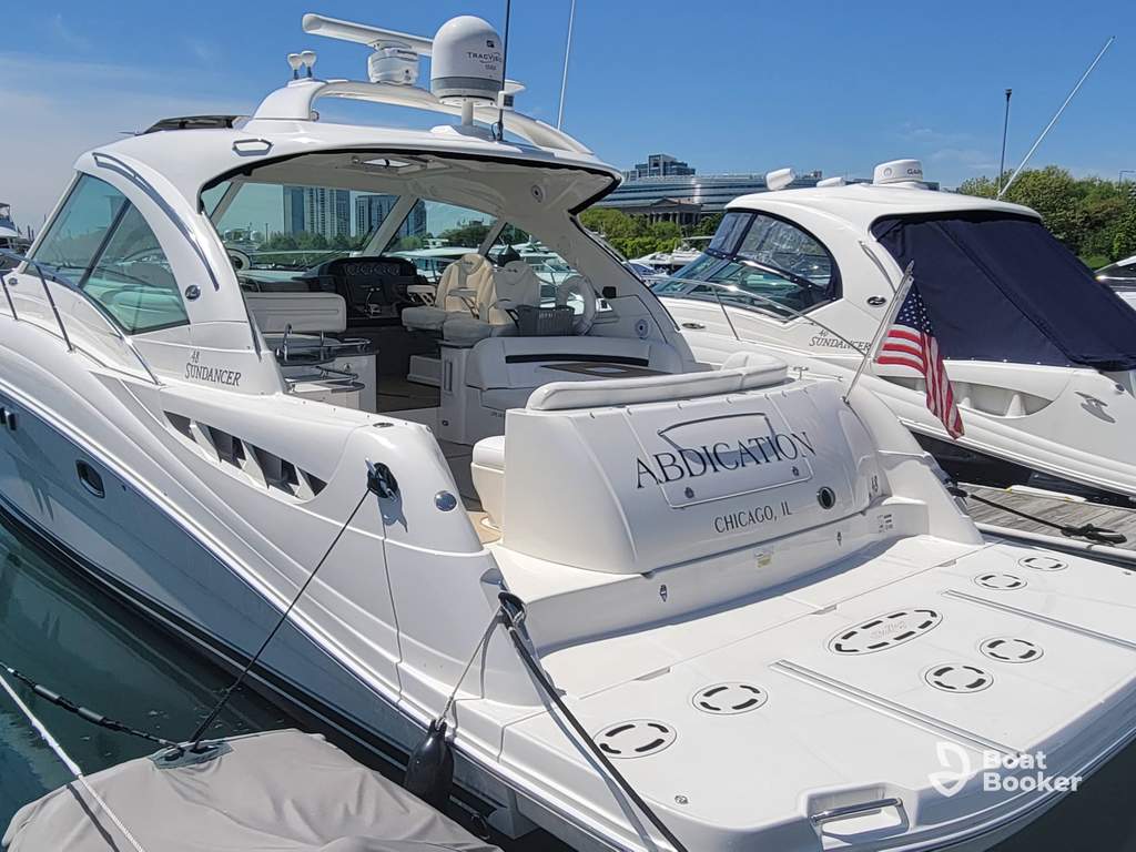 A white motor yacht called “Abdication” is docked at a marina in Chicago, IL—make sure you’ve got an Illinois boating license before sailing these waters.