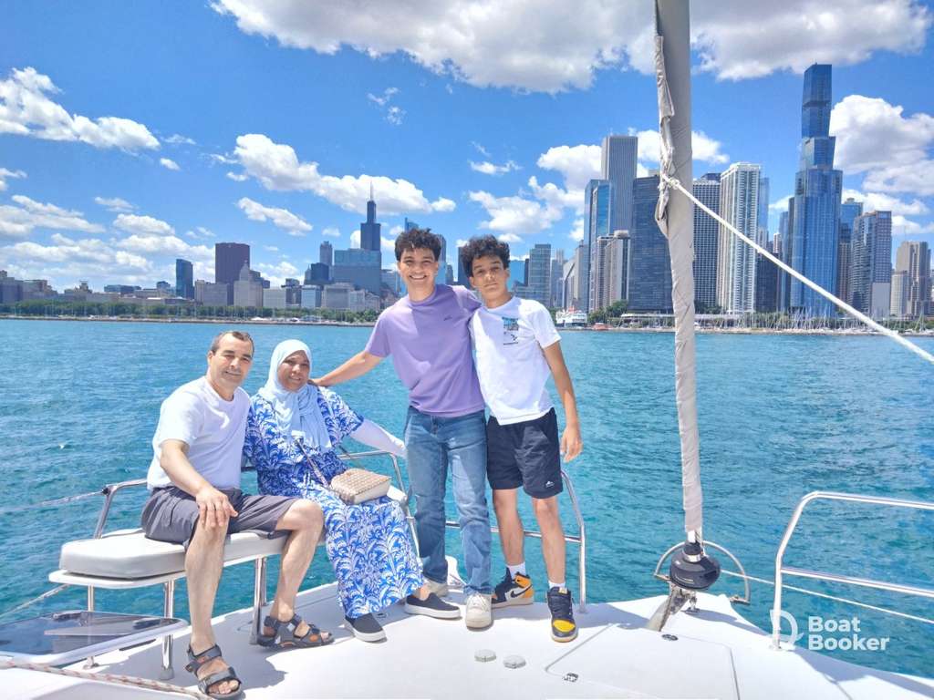 Four people are on a boat enjoying city skyline views beneath a blue sky—it’s perfect weather for anyone with an Illinois boating license to explore the water.